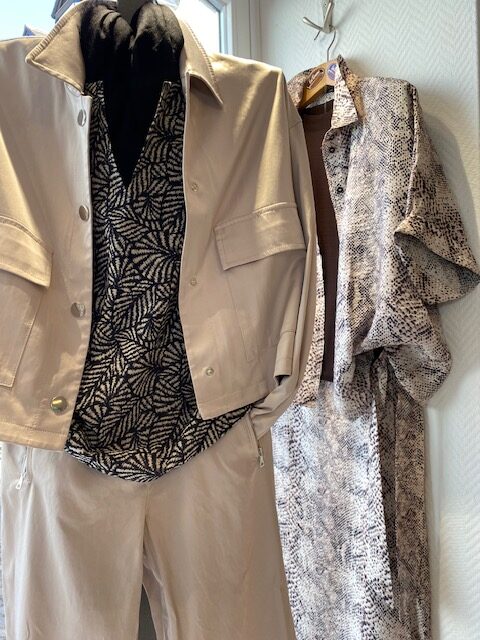 Zwei elegante Damen-Outfits: Beige Jacke, gemustertes Top; daneben ein gemustertes Kleid.