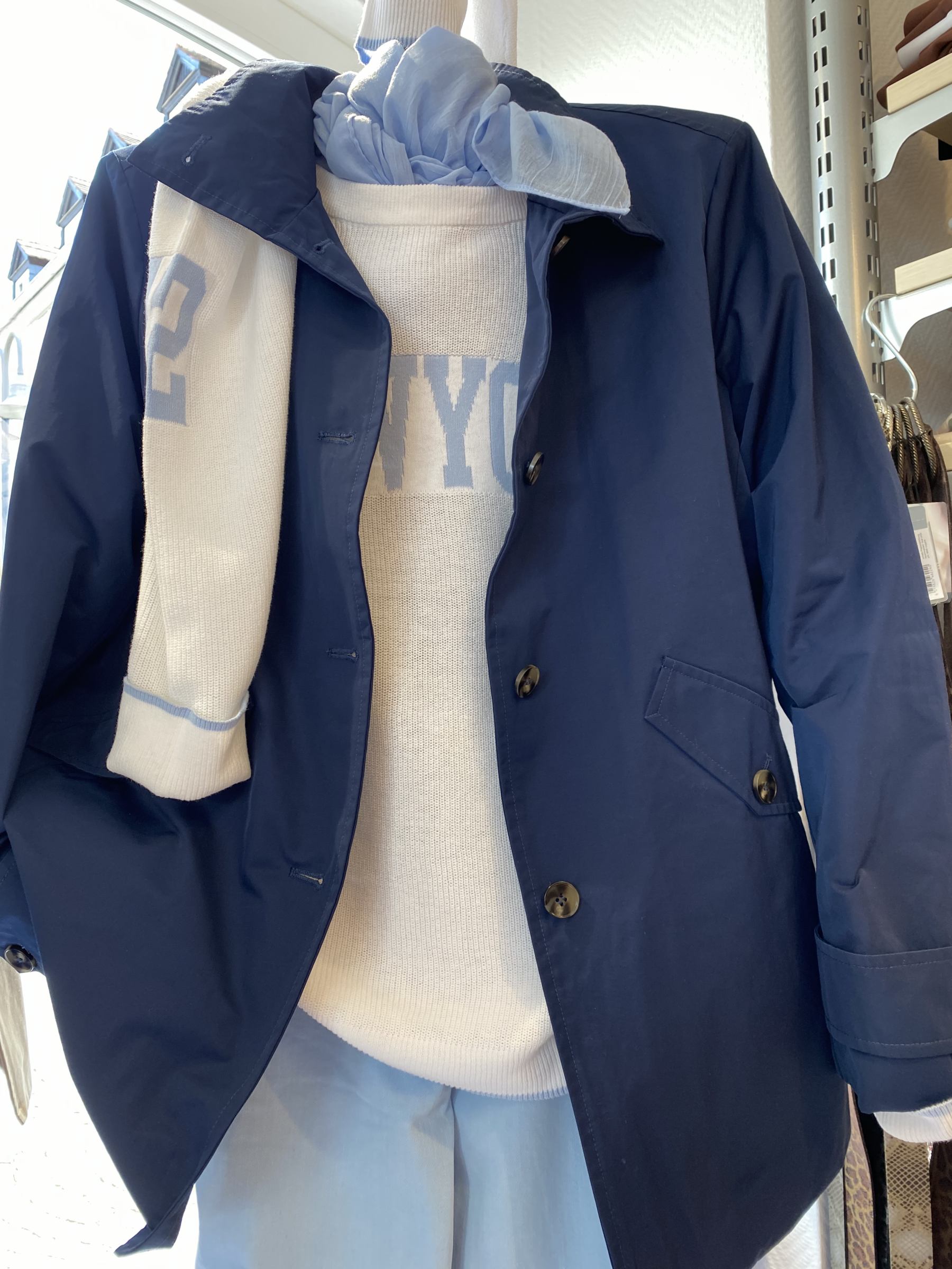 Eine Schaufensterpuppe mit einer blauen Jacke, hellblauer Hose und einem Schal, kein Gesicht sichtbar.