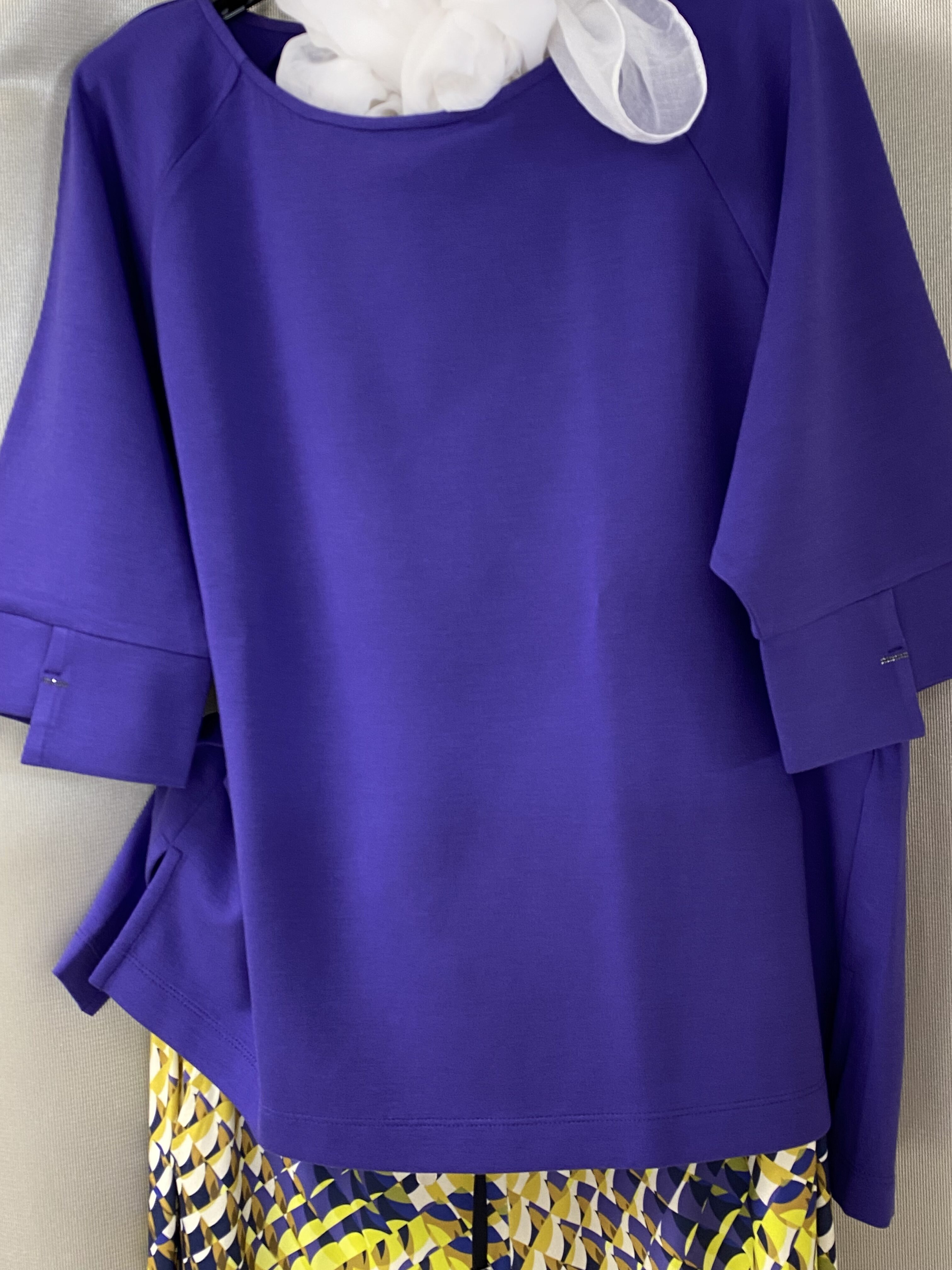 Lila Bluse, geometrisches Muster in Gelb, Schwarz und Weiß, lockere Passform, keine Person sichtbar.
