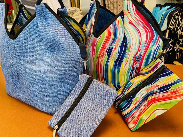 Taschen in Jeans- und buntem Streifenmuster auf einem Tisch, lebendige Farben und Muster.