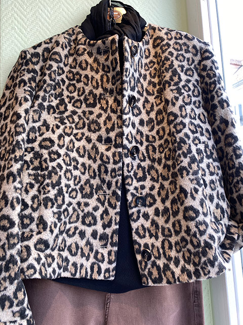 Eine Jacke mit Leopardenmuster in Beige und Schwarz hängt an einem Haken.