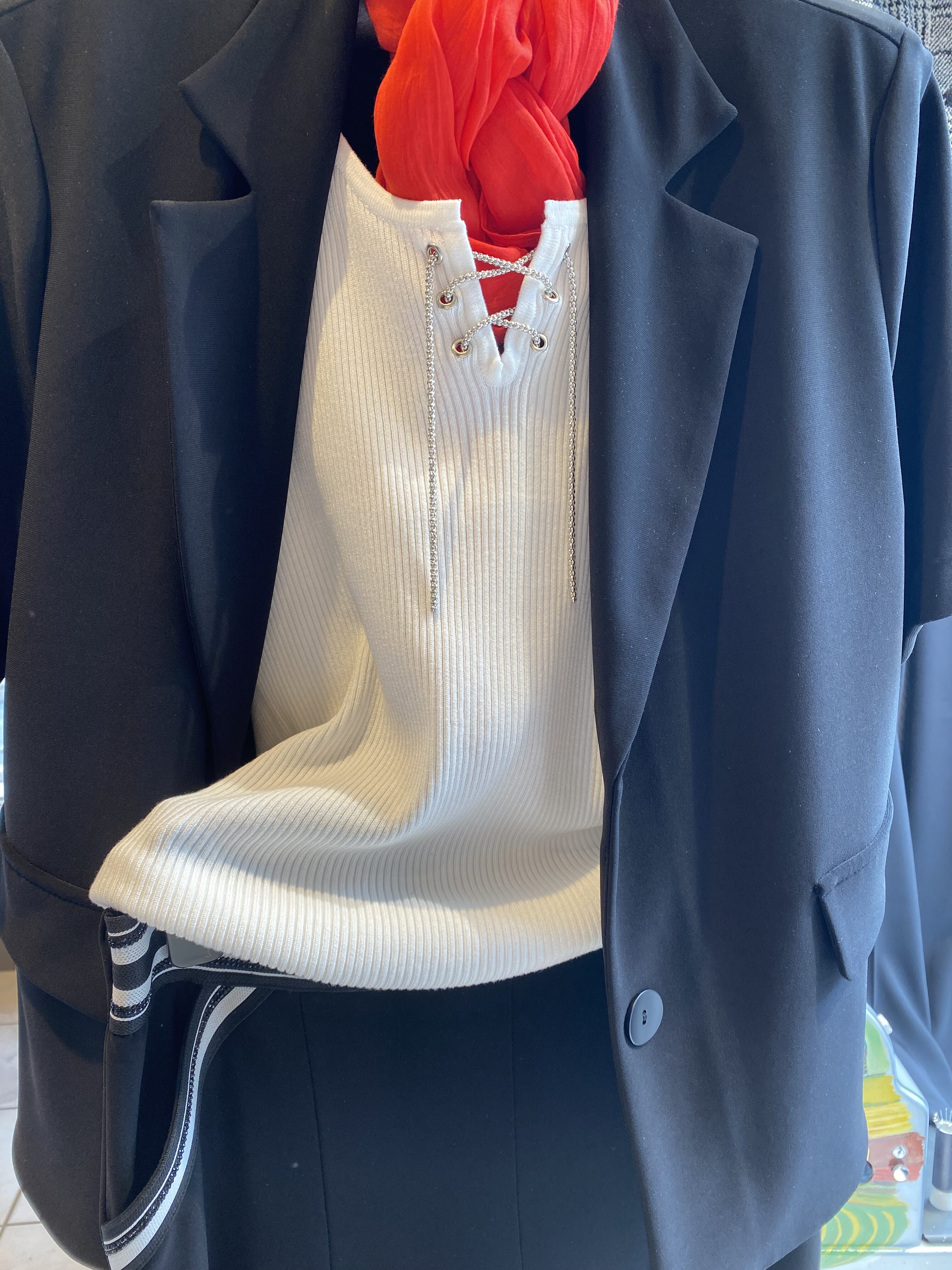 Ein stilvolles Outfit mit schwarzem Blazer, weißem Oberteil und rotem Schal