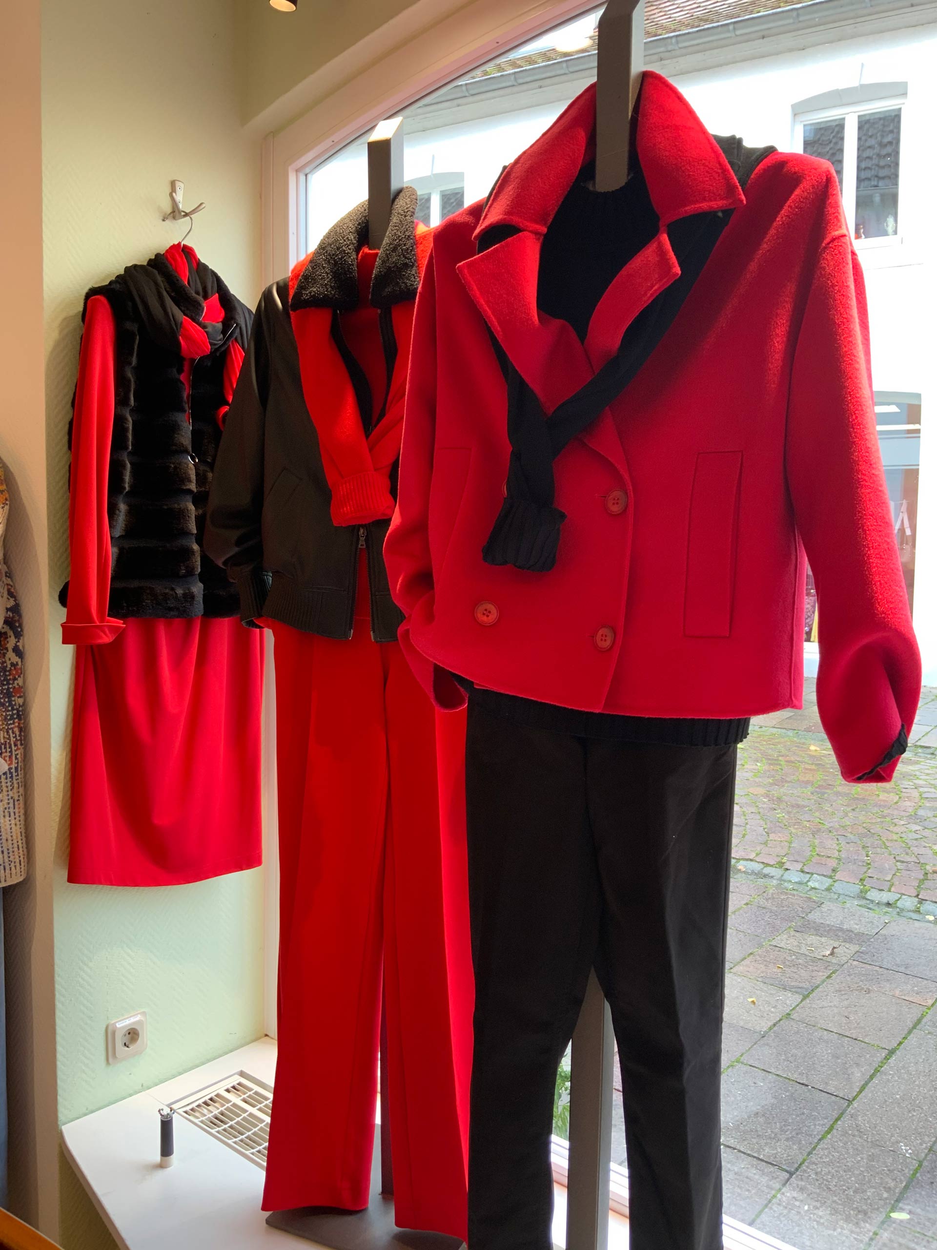 Drei Schaufensterpuppen tragen stilvolle rote Outfits mit schwarzen Akzenten