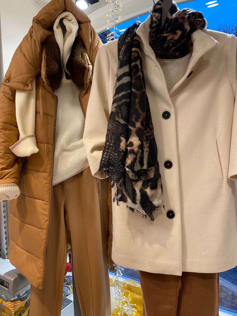 Zwei Schaufensterpuppen tragen stilvolle Winterkleidung in Braun und Creme mit Schal
