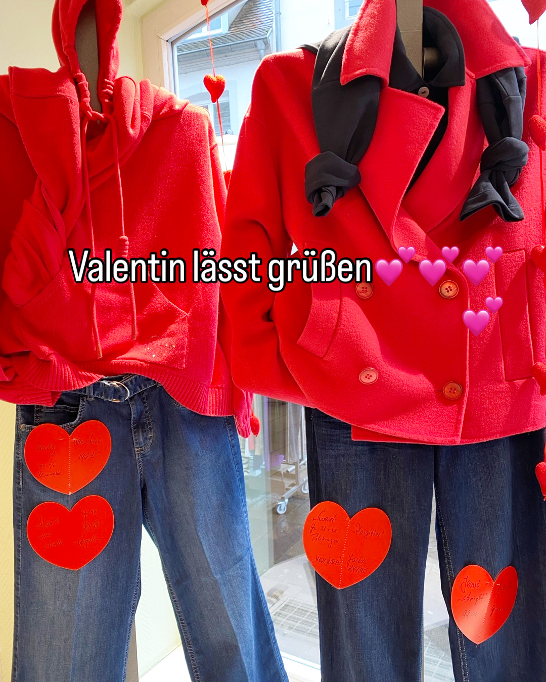 Zwei Schaufensterpuppen tragen rote Oberteile und blaue Jeans mit Herzanhängern