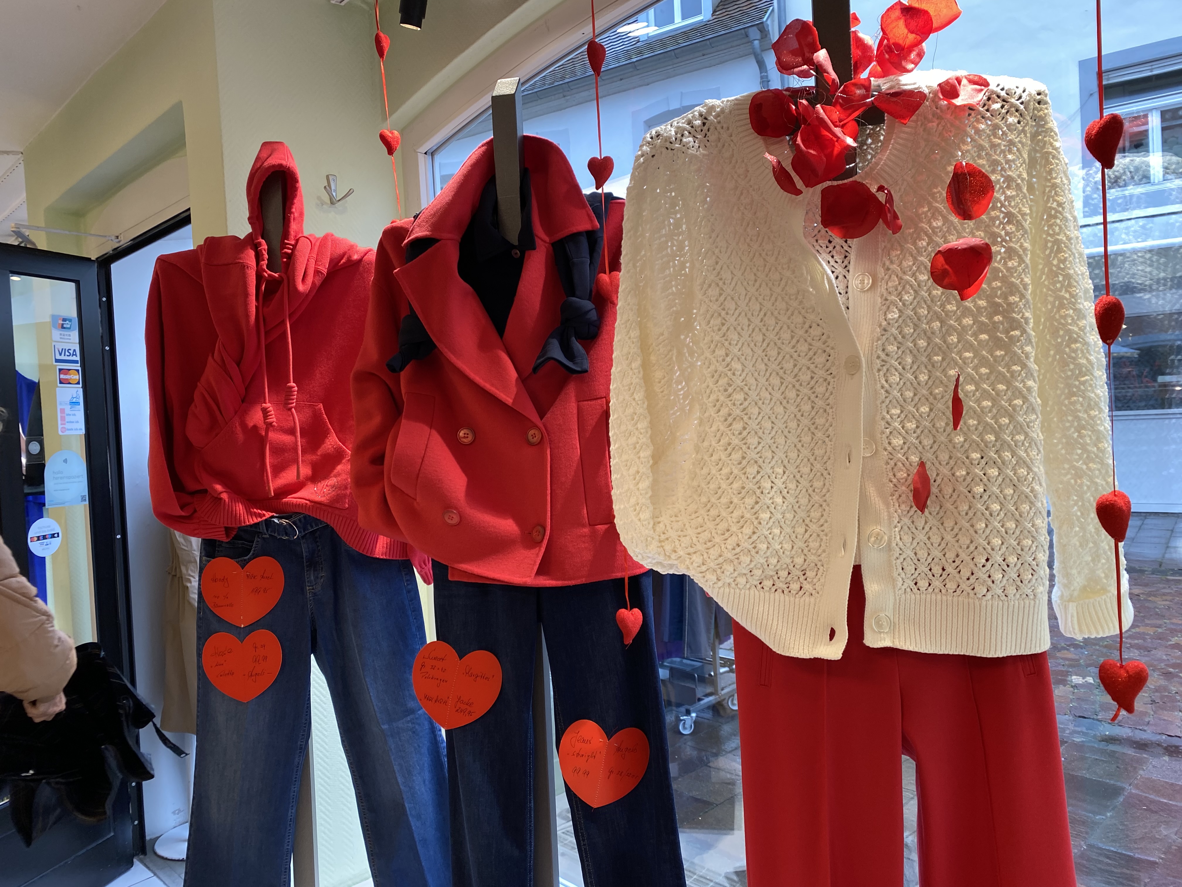 Drei Schaufensterpuppen tragen rote und weiße Kleidung mit Herzdekorationen