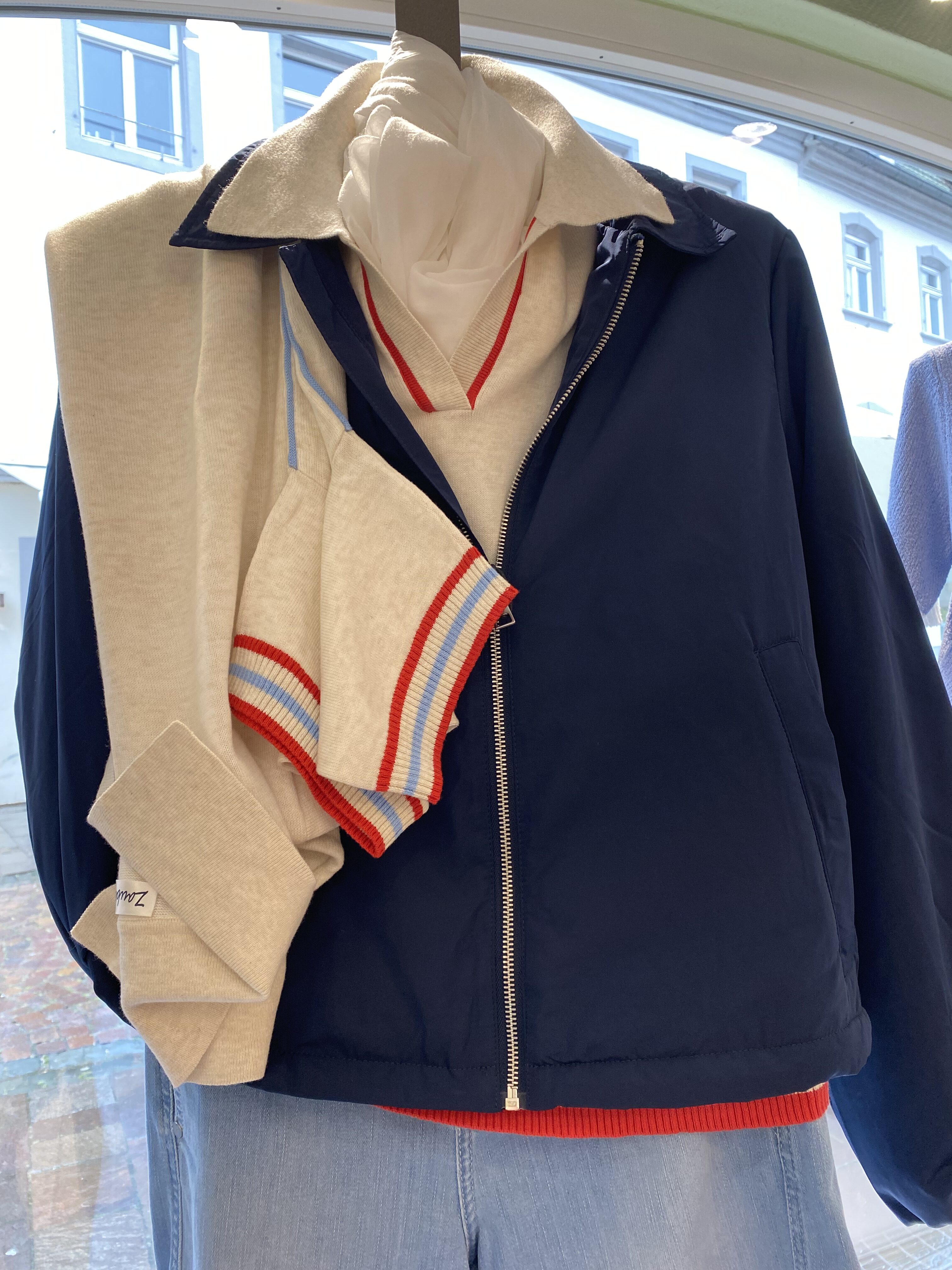 Eine Schaufensterpuppe trägt eine dunkelblaue Jacke mit hellem Pullover und Schal