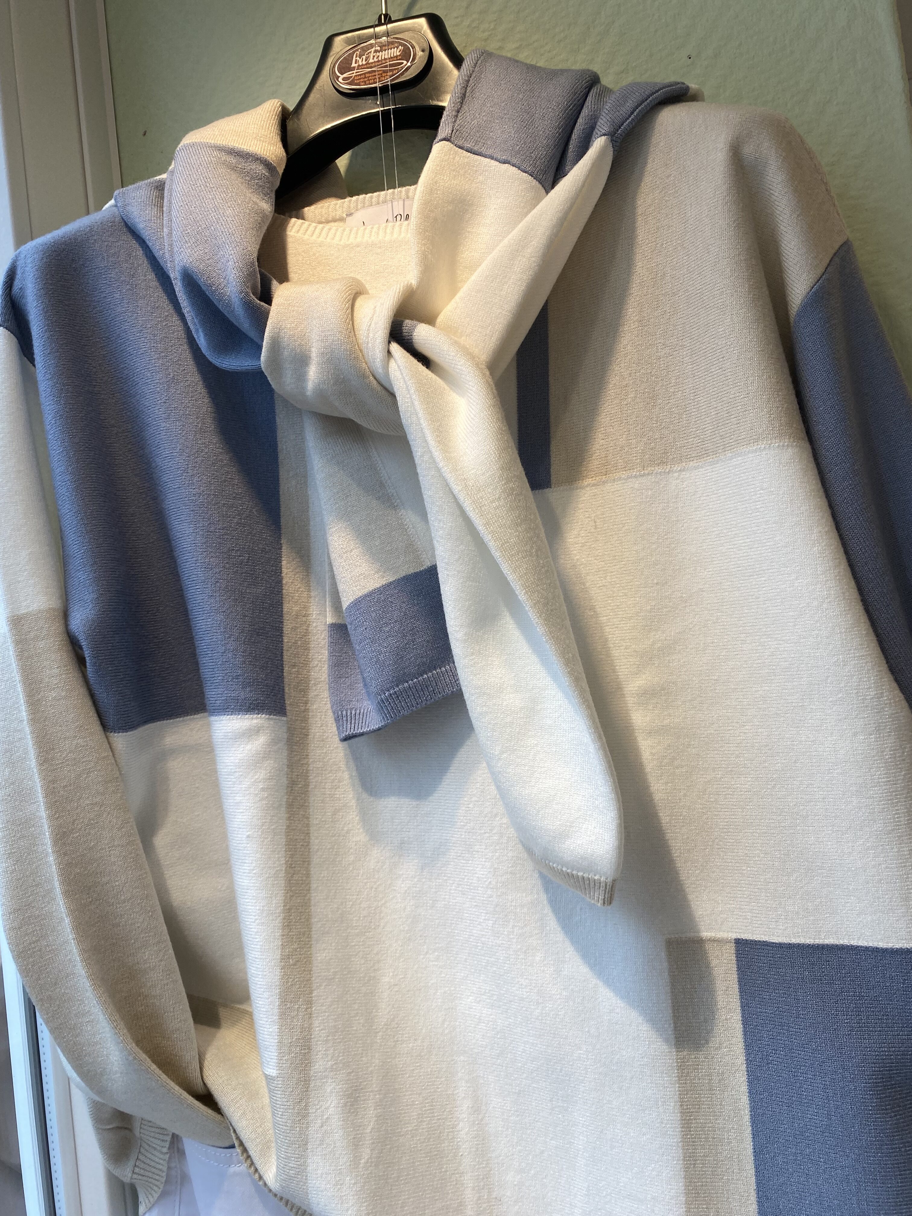 Ein Pullover mit großen blauen und cremefarbenen Karos und interessantem Knotendetail