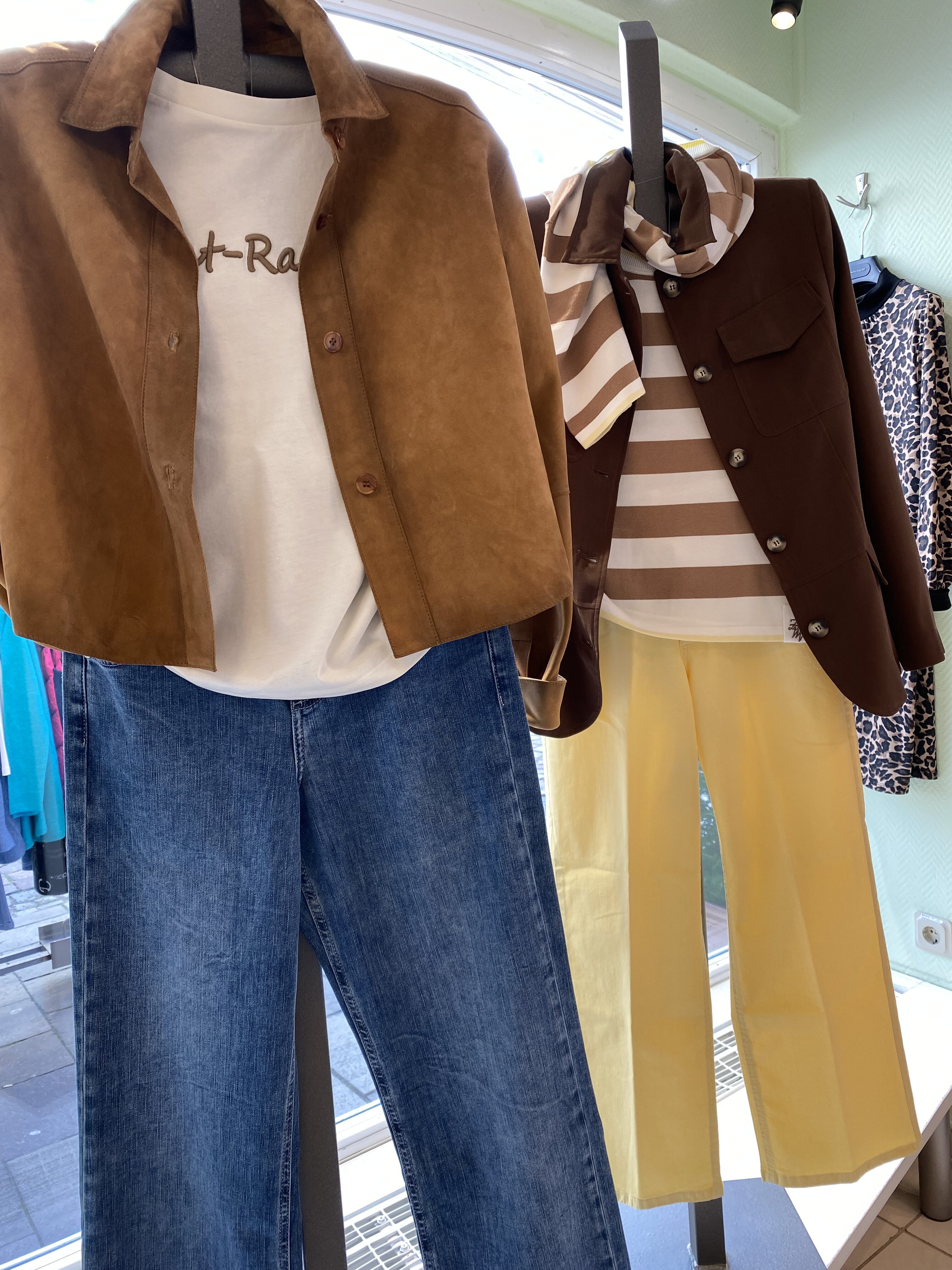 Zwei Schaufensterpuppen tragen lässige Outfits mit Braun, Gelb und Jeans sowie Streifenmuster