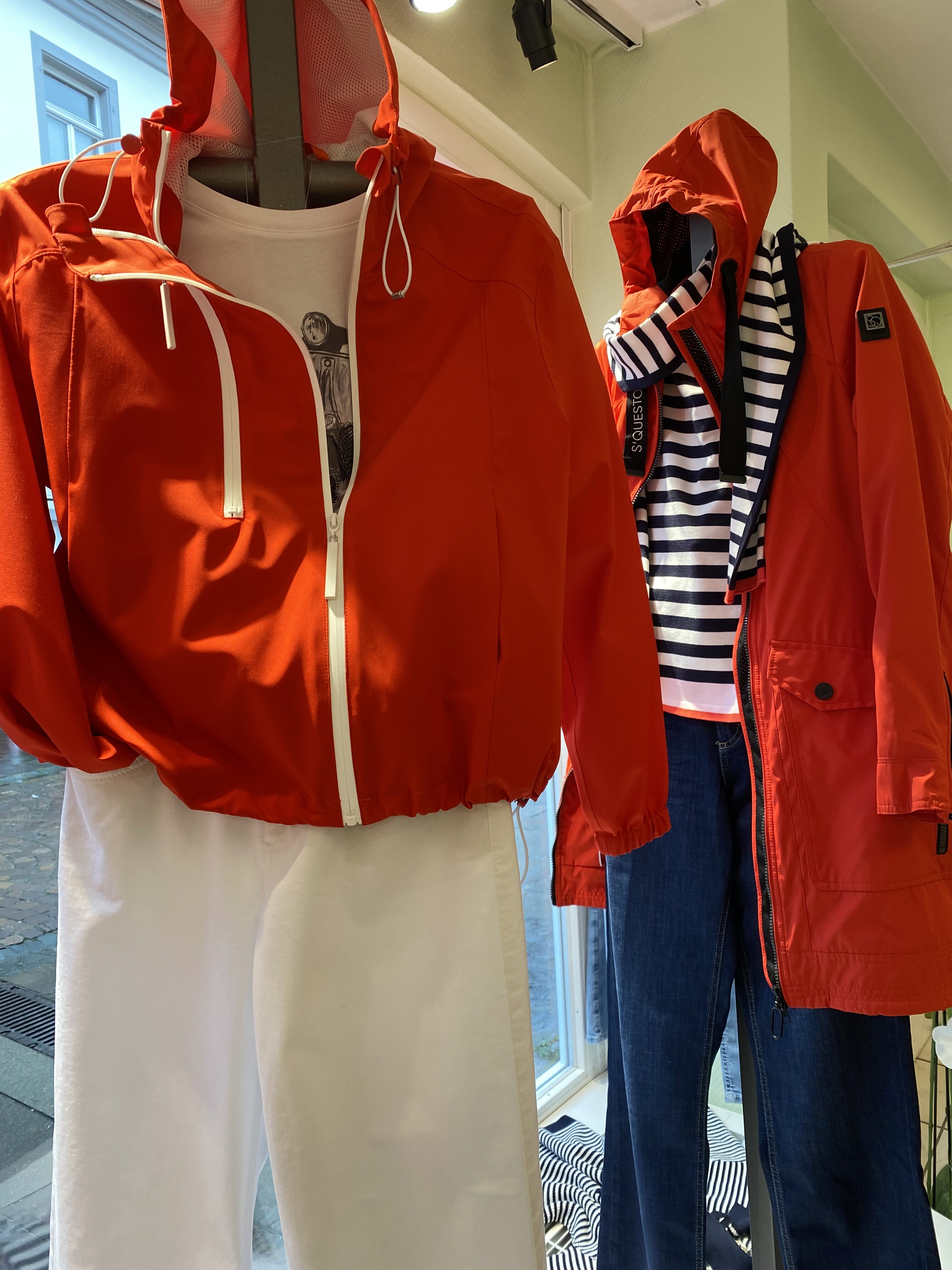 Zwei Schaufensterpuppen tragen leuchtend rote Jacken mit Streifen und weißen Hosen
