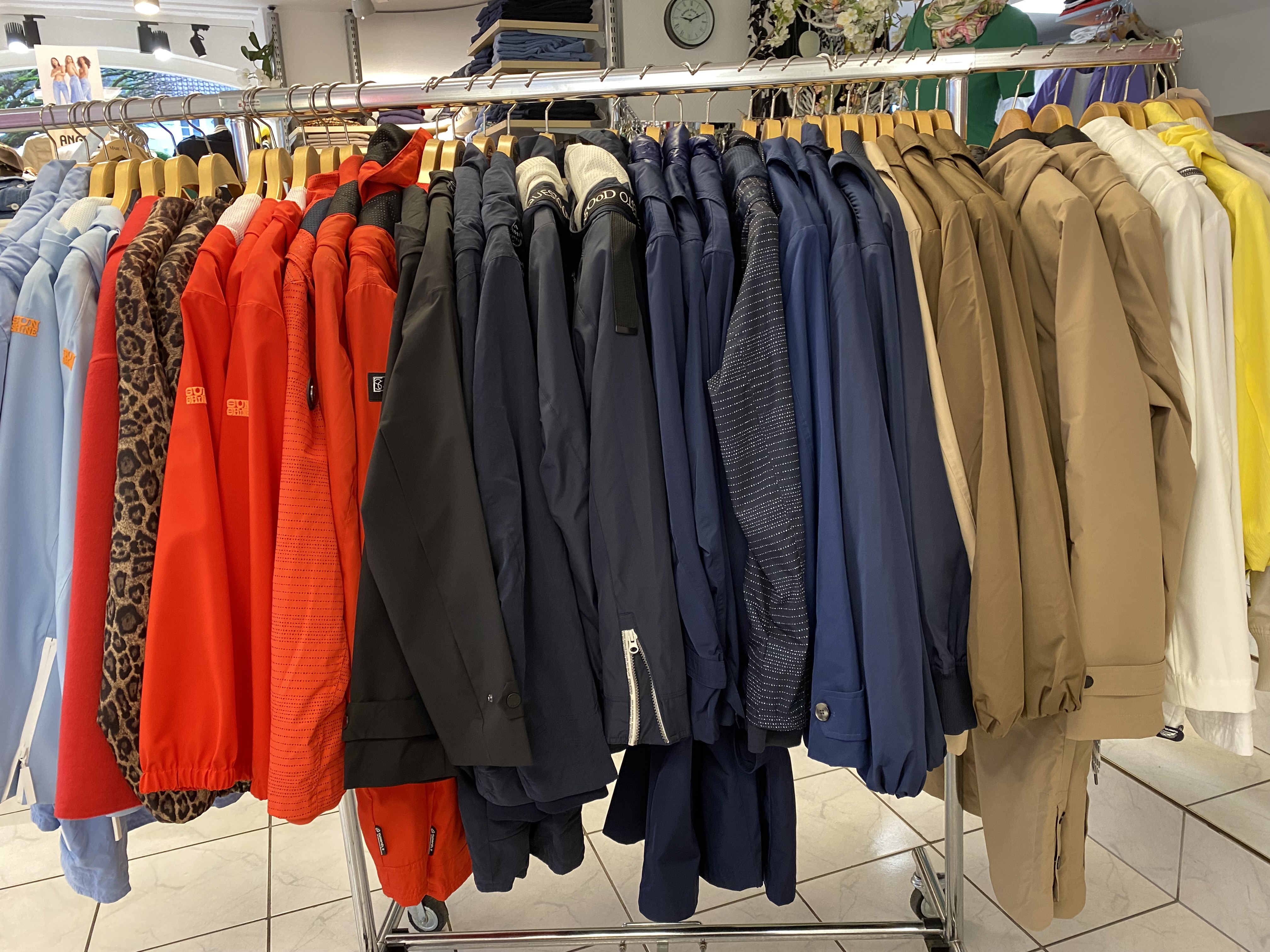 Verschiedene bunte Jacken hängen ordentlich auf Kleiderbügeln in einem Geschäft