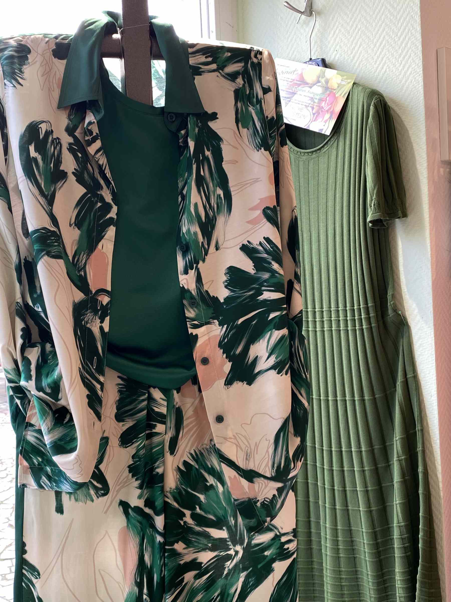 Zwei grüne Damenkleider, eines mit Blattmuster und grünem Top, das andere uni grün