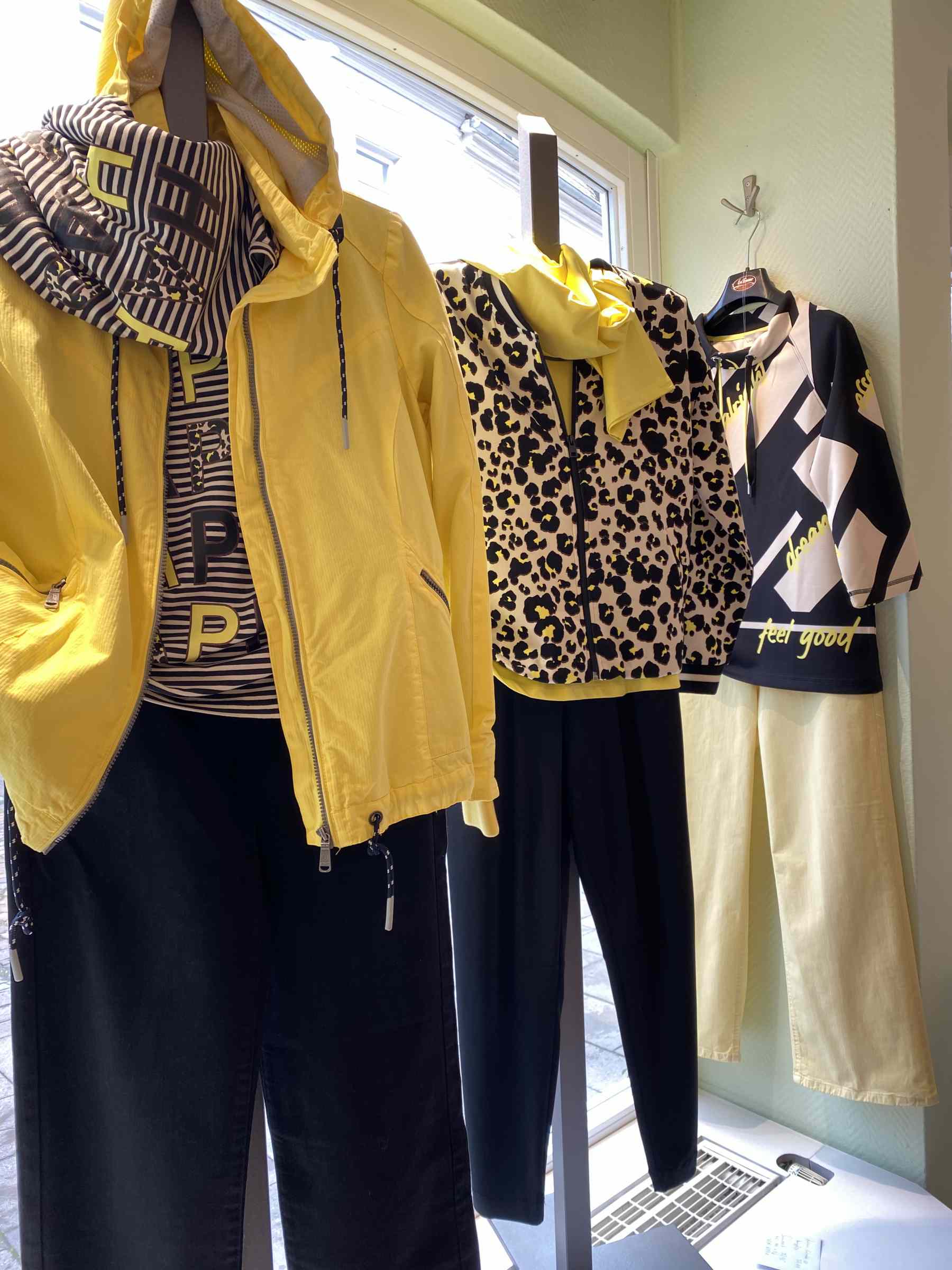 Vier Schaufensterpuppen tragen modische gelb-schwarze Outfits mit auffälligen Mustern