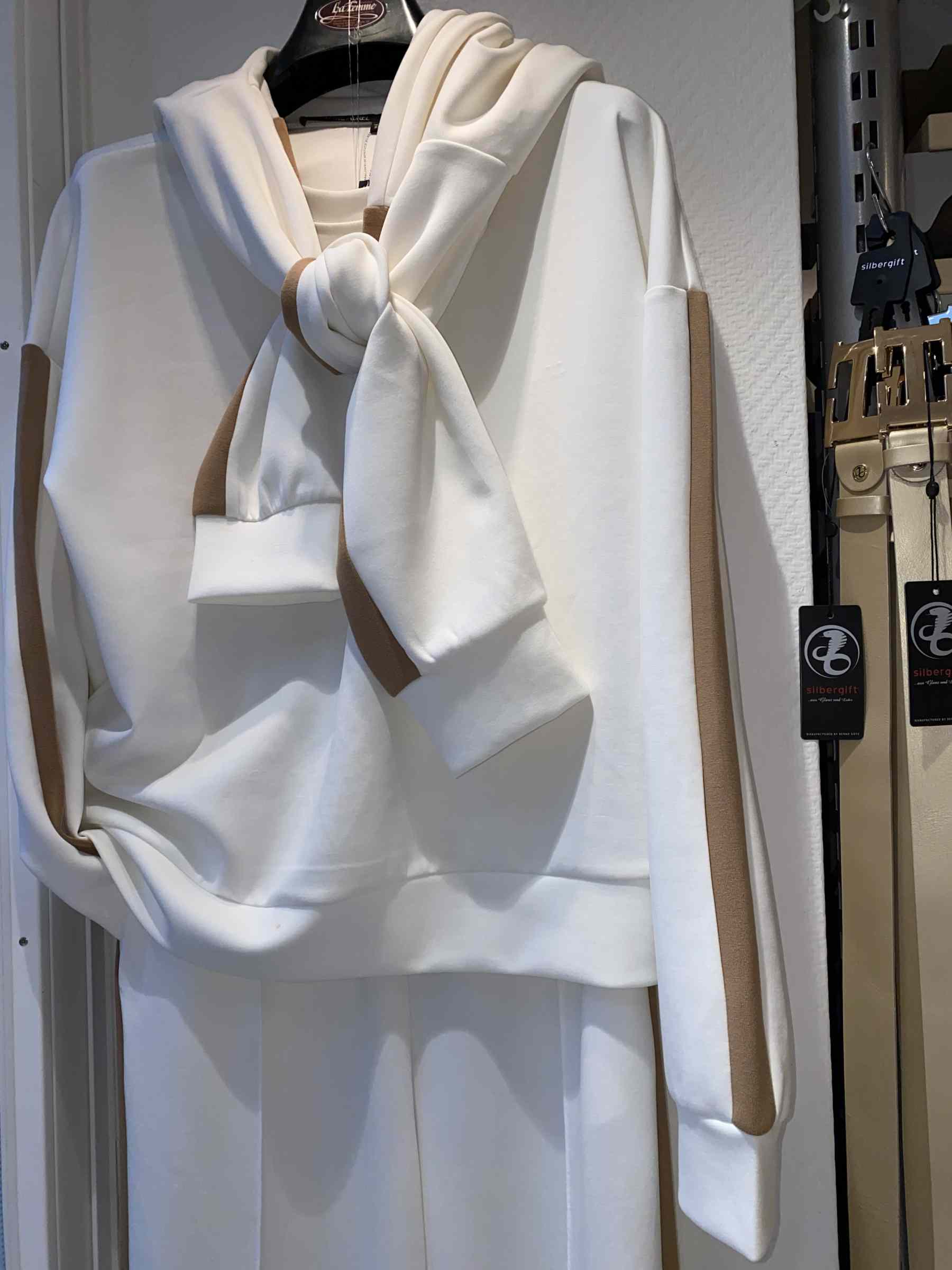 Ein cremefarbenes Sweatshirt mit beigem Streifen und auffallend großen Schleifenärmeln