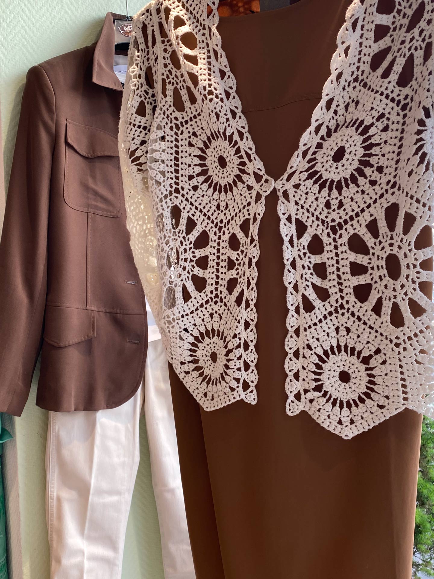 Braune Schaufensterpuppe mit Häkelweste und braunem Blazer im Hintergrund