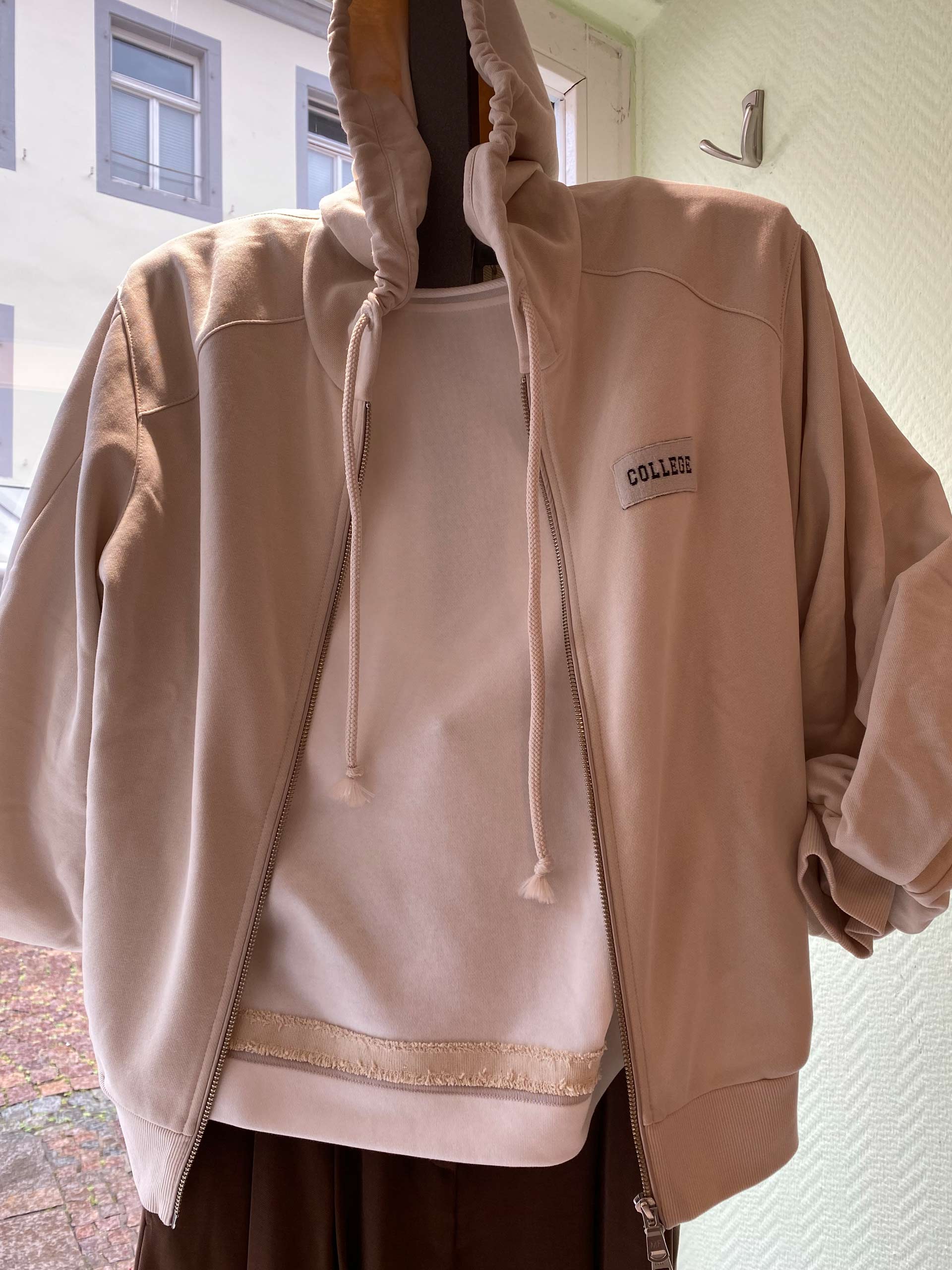 Person ohne Gesicht, neutral, beige Kapuzenjacke, COLLEGE Patch