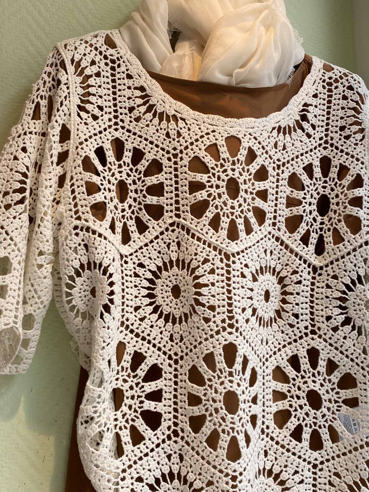 Puppe ohne Gesicht in weißer Häkelbluse mit Blumenmuster und Tuchkragen