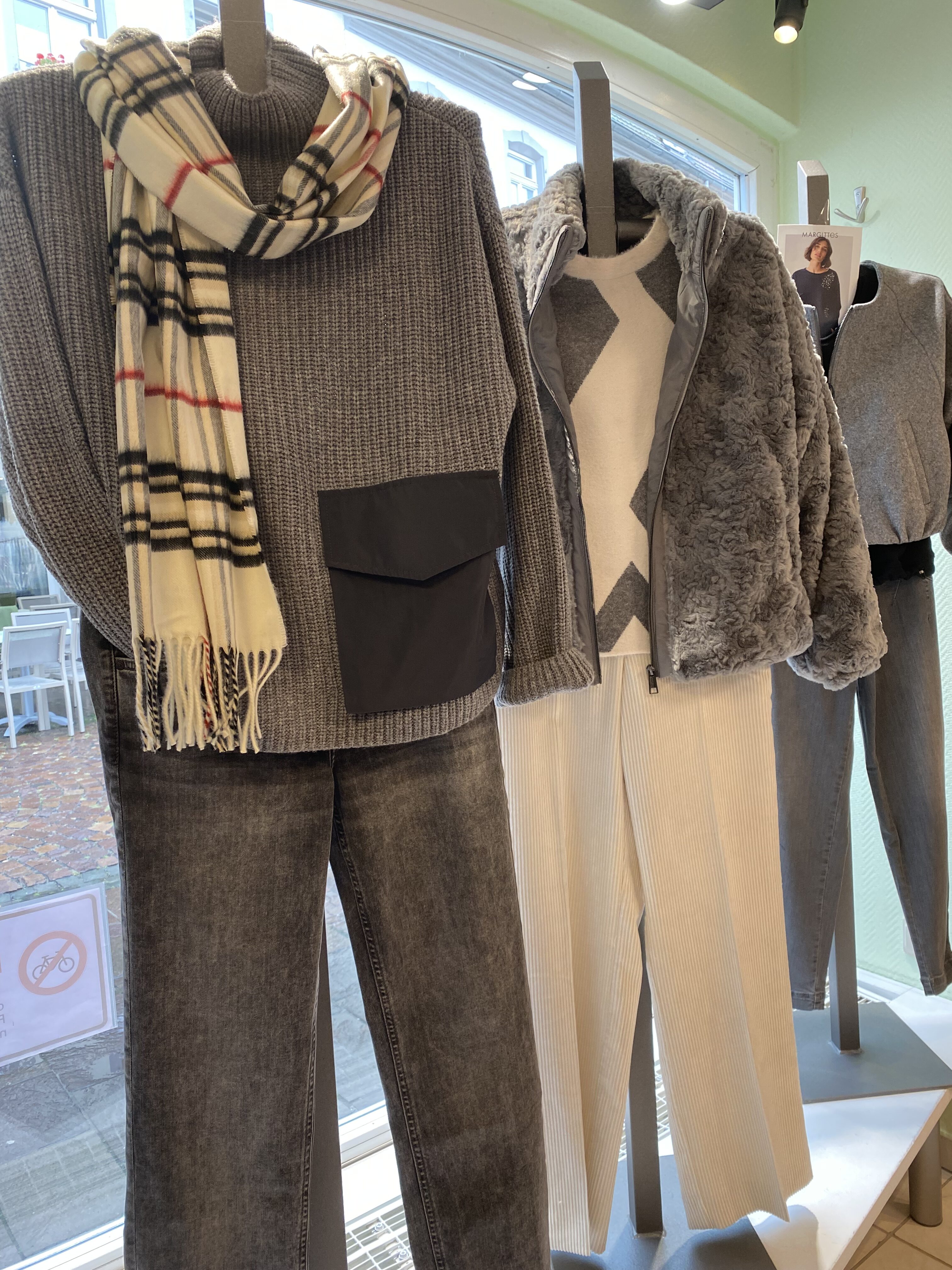 Schaufensterpuppen mit grauen Strickpullovern kariertem Schal und Kunstfelljacke