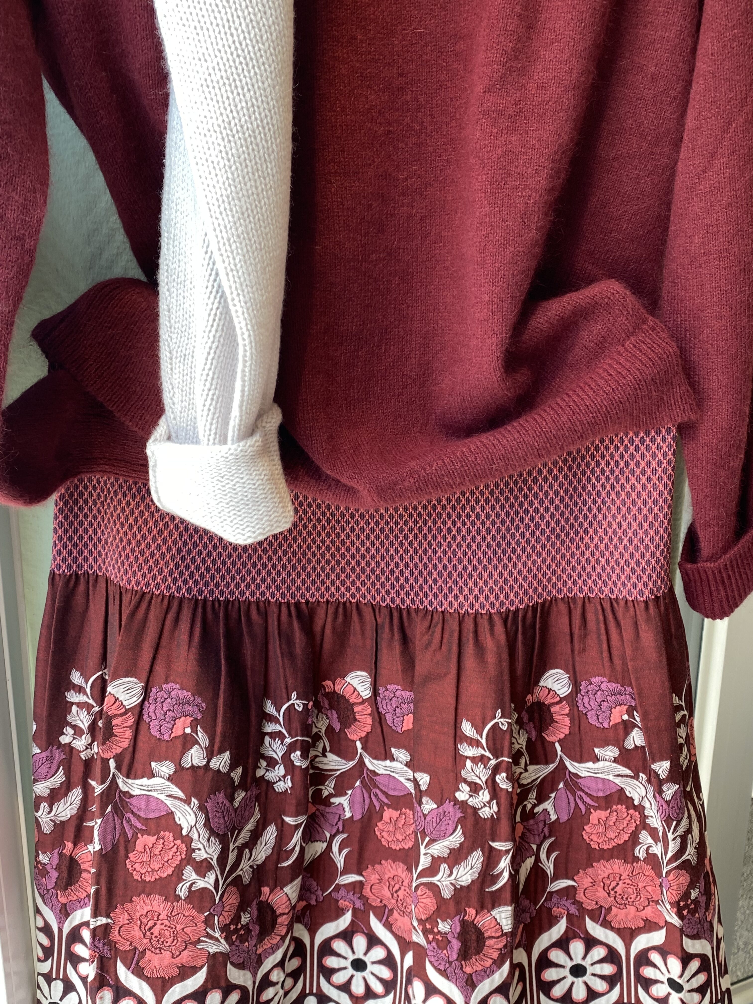 Weinroter Strickpullover ueber einem Kleid mit Blumenmuster in Rosa und Lila