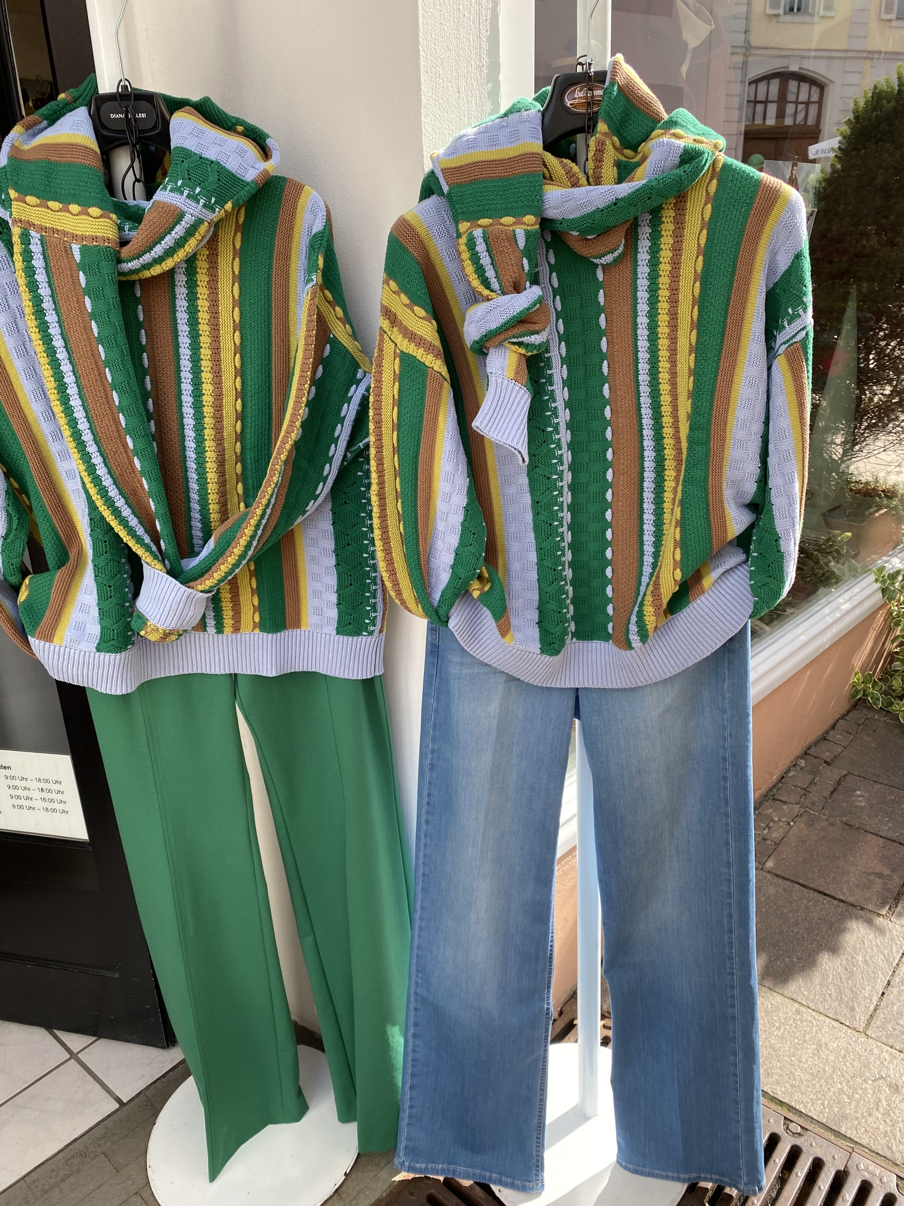 Zwei gestreifte Strickpullover mit gruener Hose und Jeans im Schaufenster