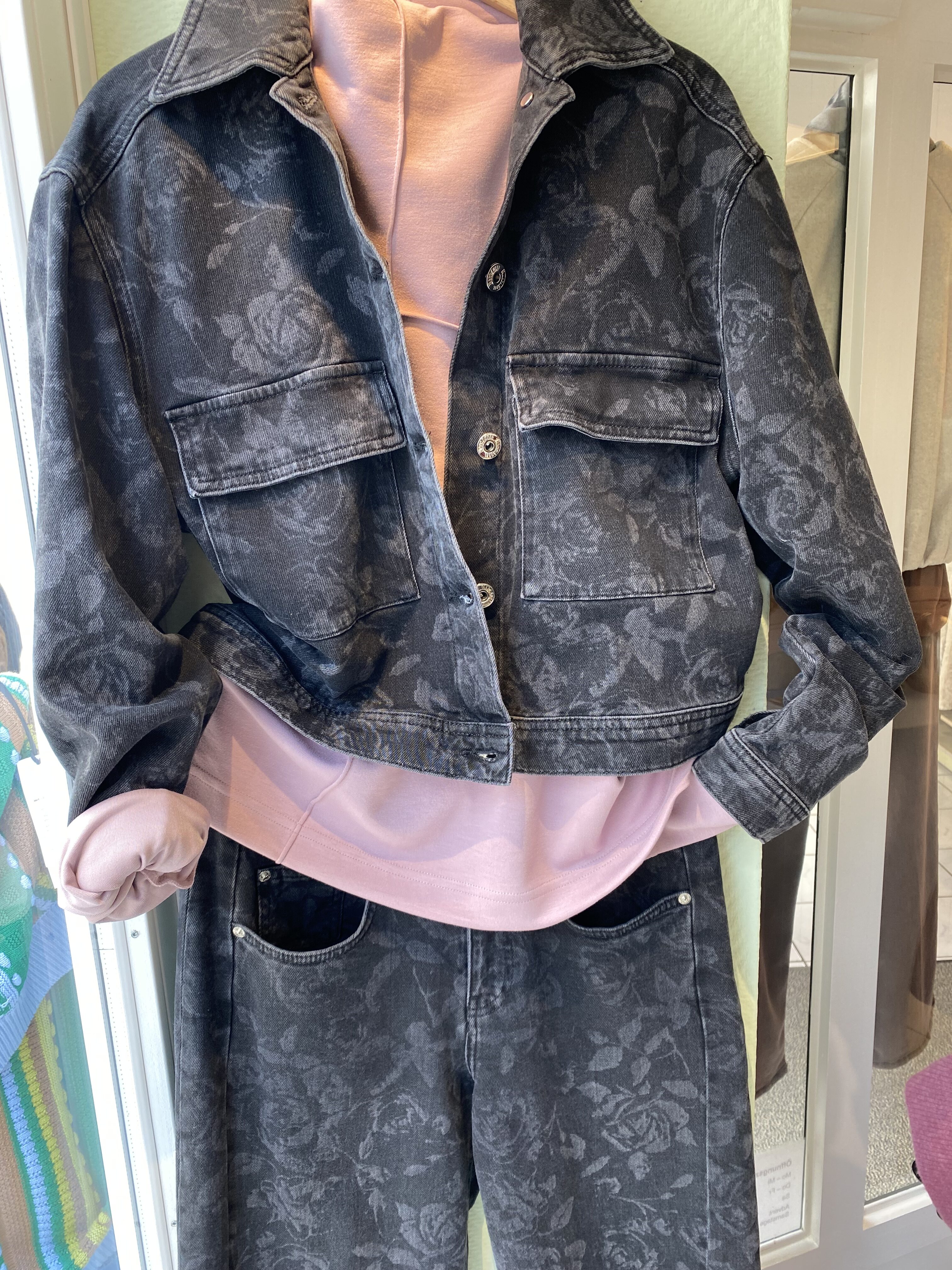 Schaufensterpuppe mit grauer Jeansjacke mit Blumenmuster und rosa Oberteil