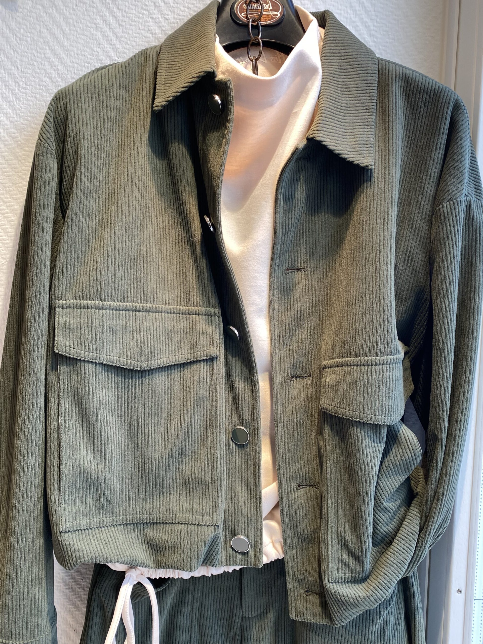Olivgruene Cordjacke mit Druckknoepfen ueber einem hellrosa Oberteil